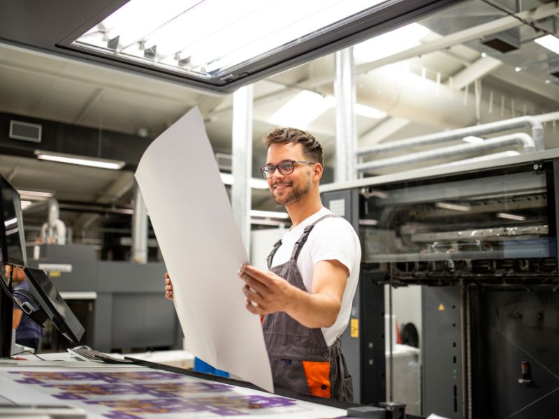 Print shop employee looking at finished poster.